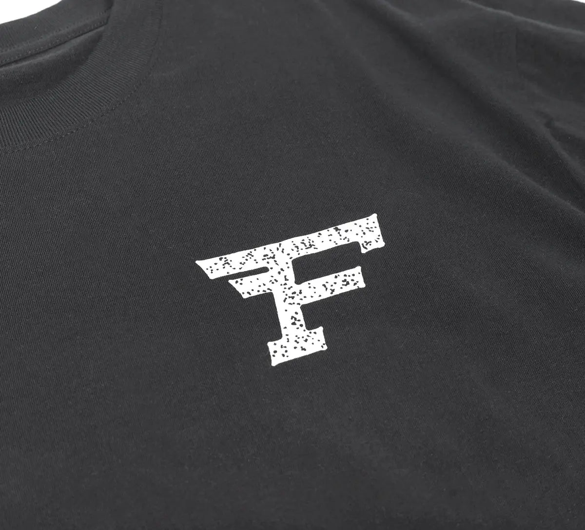 Close-up of Arthur Black Tee showing White speckled F logo with distressed texture on charcoal fabric - Slowride Supply