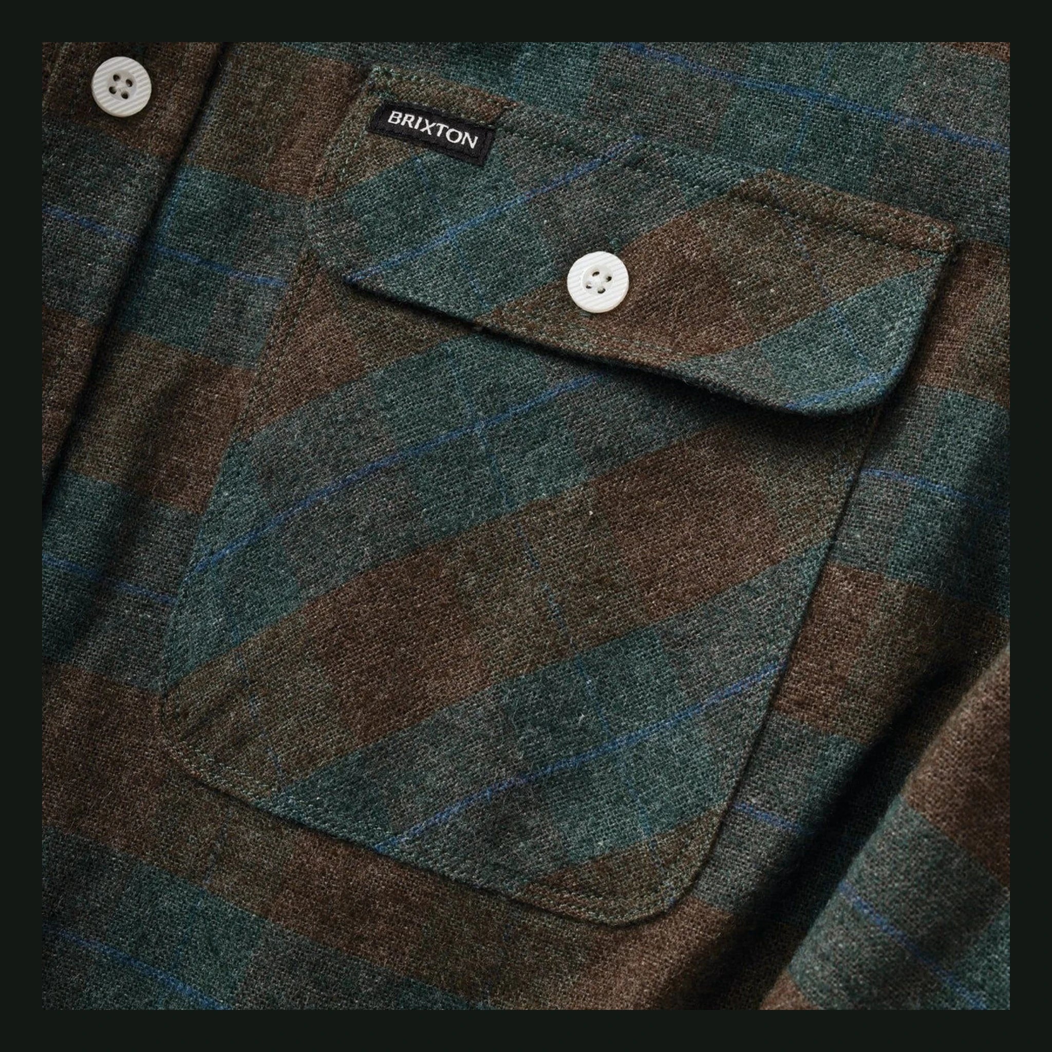Close-up of Bowery Flannel Ocean L/S Woven L/S Woven showing White four-hole button on chest pocket, teal and brown plaid