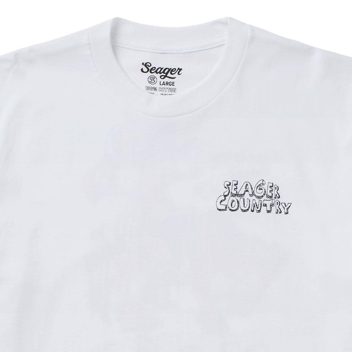 Close-up of Donde White Tee showing White cotton tee with small outlined graphic text on right chest reading "Seager Country