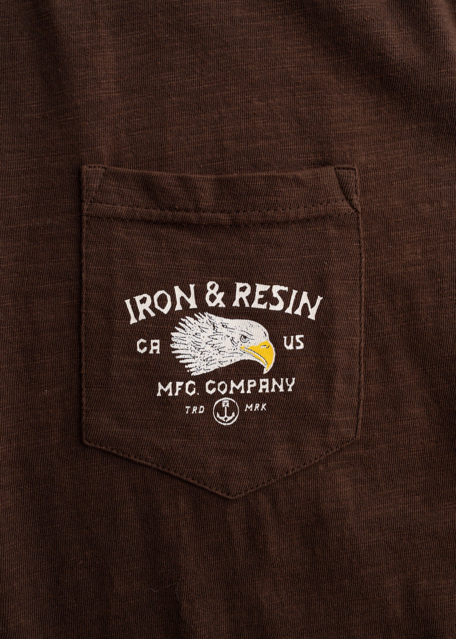 Close-up of Don't Ruin It Brown Tee showing Chest pocket with embroidered eagle head and "Iron & Resin" text graphic -