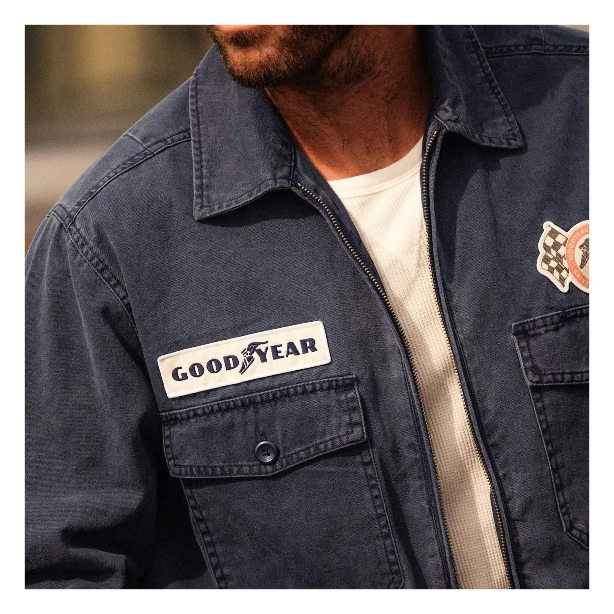 Person wearing Goodyear Trademark LW Washed Navy Jacket, Man wearing navy jacket outdoors in soft daylight setting -