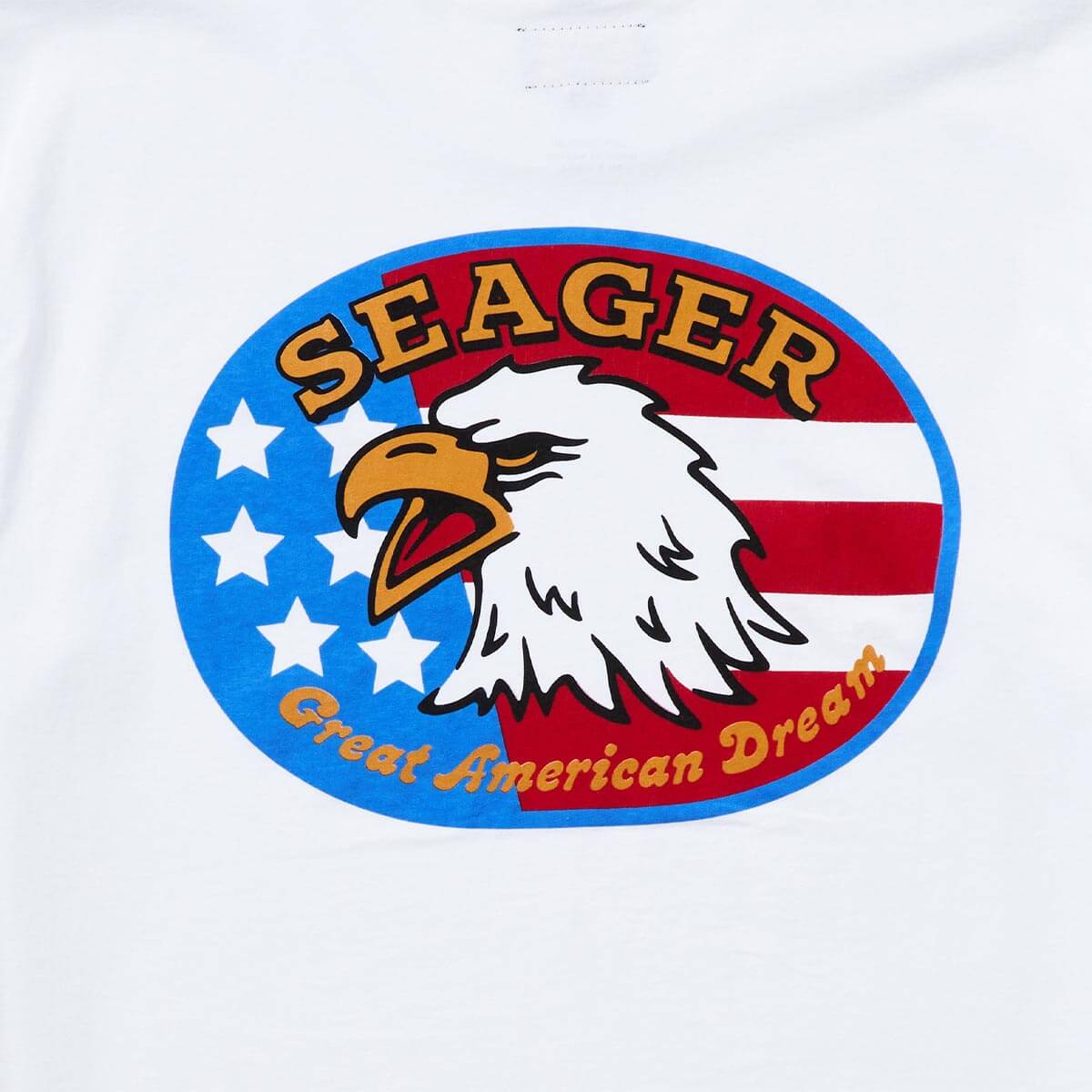 Close-up of Great American Dream White Tee showing Oval badge with white eagle head, gold and red beak, "SEAGER" in gold