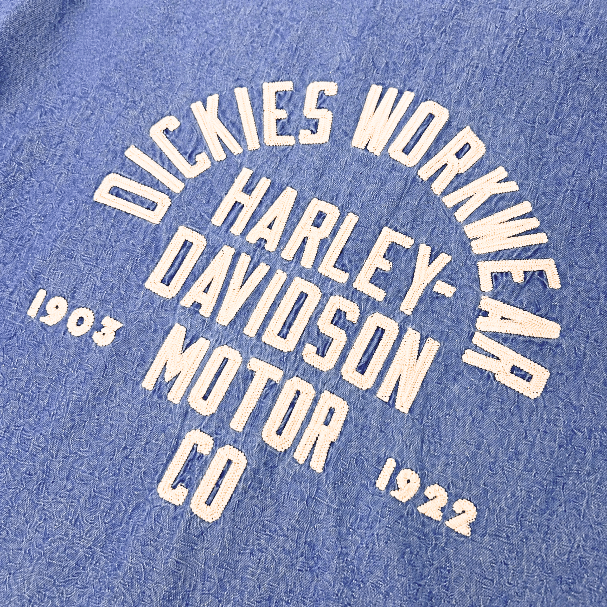 Close-up of Hdxdickies Chambray Work Shirt Light Wash Denim S/S Woven S/S Woven showing Cream-colored circular text graphic