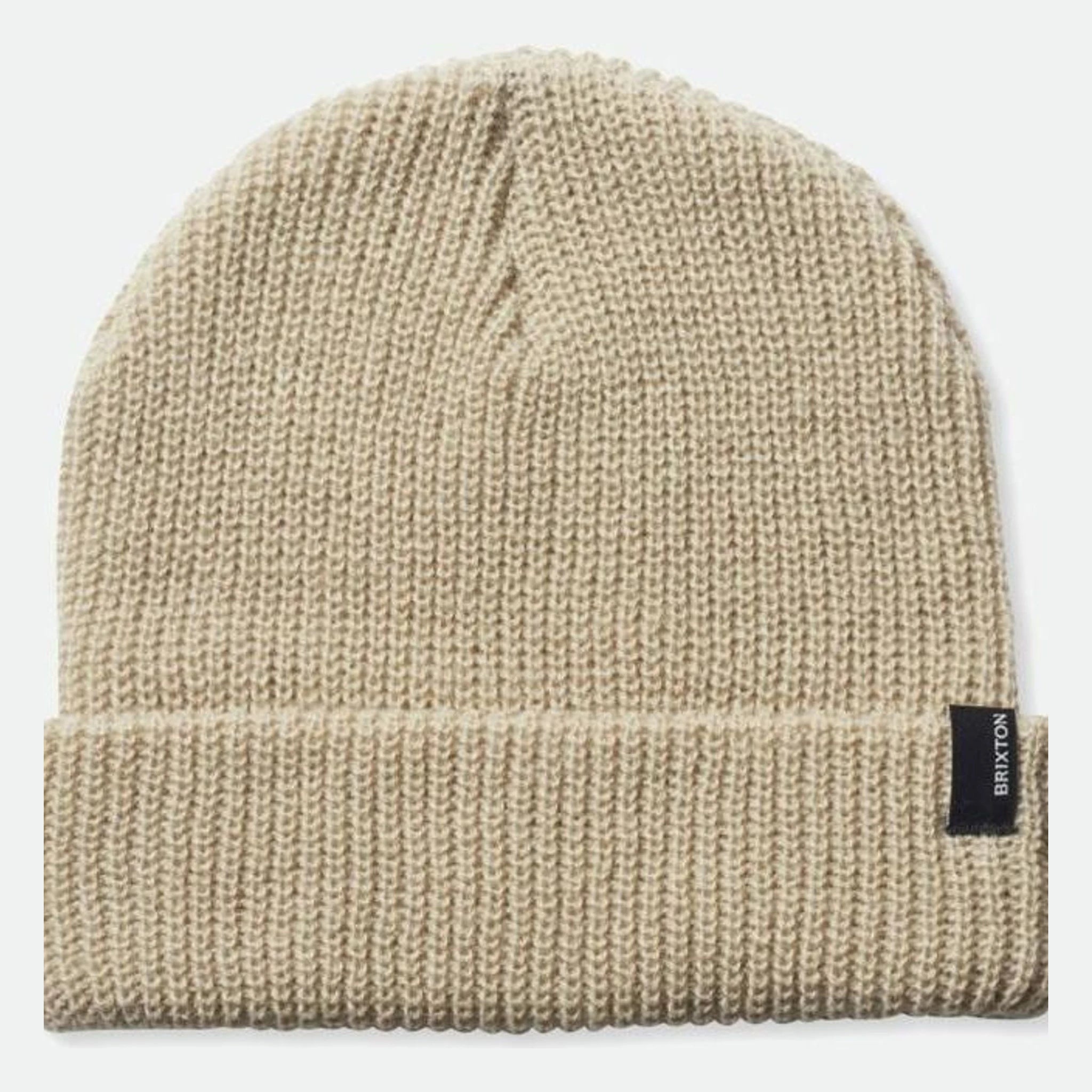 Close-up of Heist Mustard Beanie showing Cream knit fabric with vertical ribbed texture and black woven label tag on side -