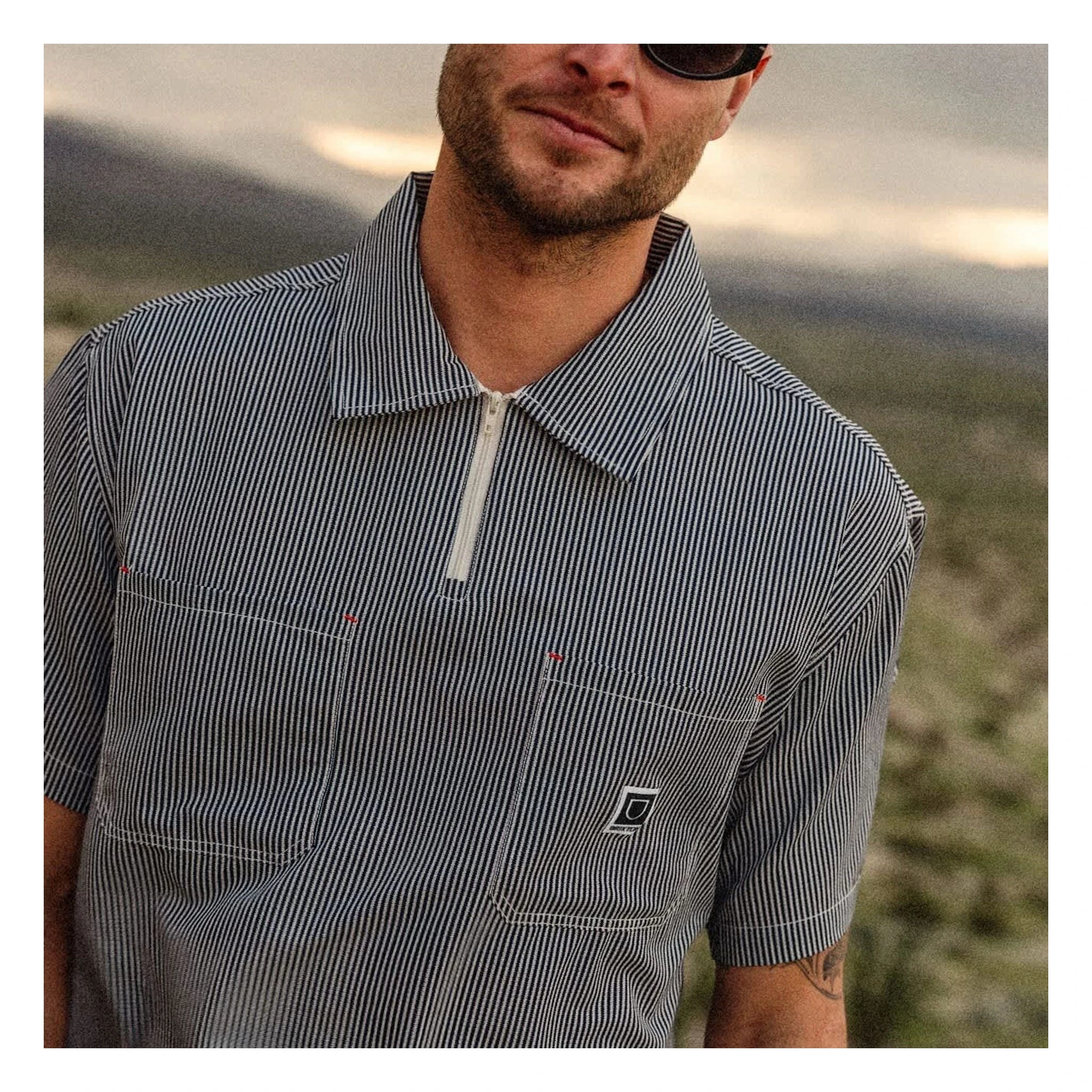 Person wearing Journey LW SS Woven Navy/white Stripe S/S Woven S/S Woven, Desert landscape with rolling hills and overcast