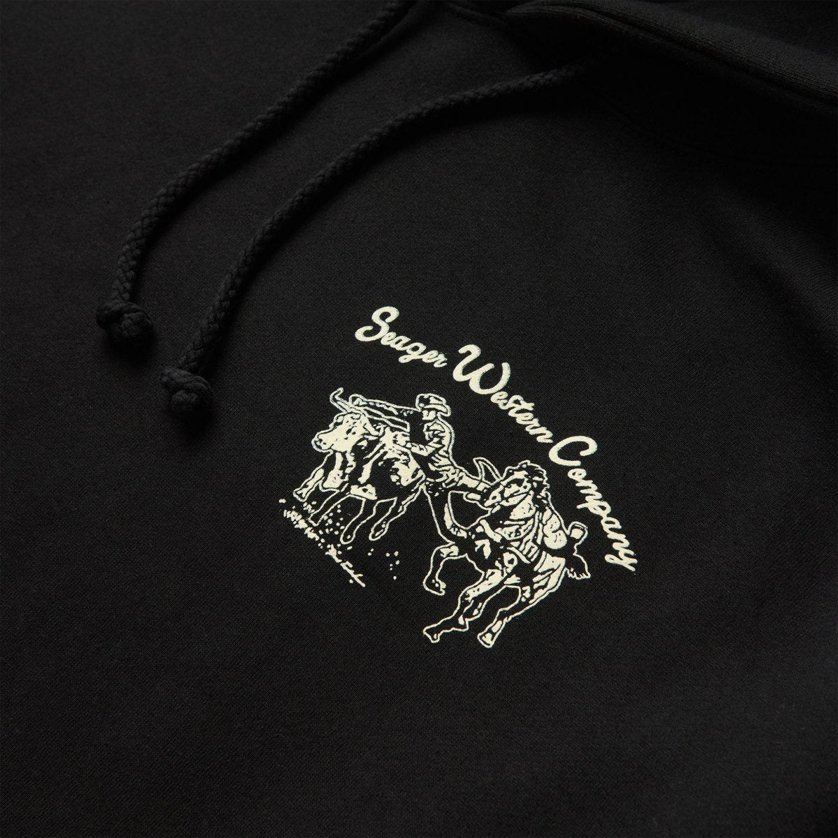 Close-up of Los Rios Black Hoodie showing Cream embroidered graphic showing cowboy on bucking horse with script text above -