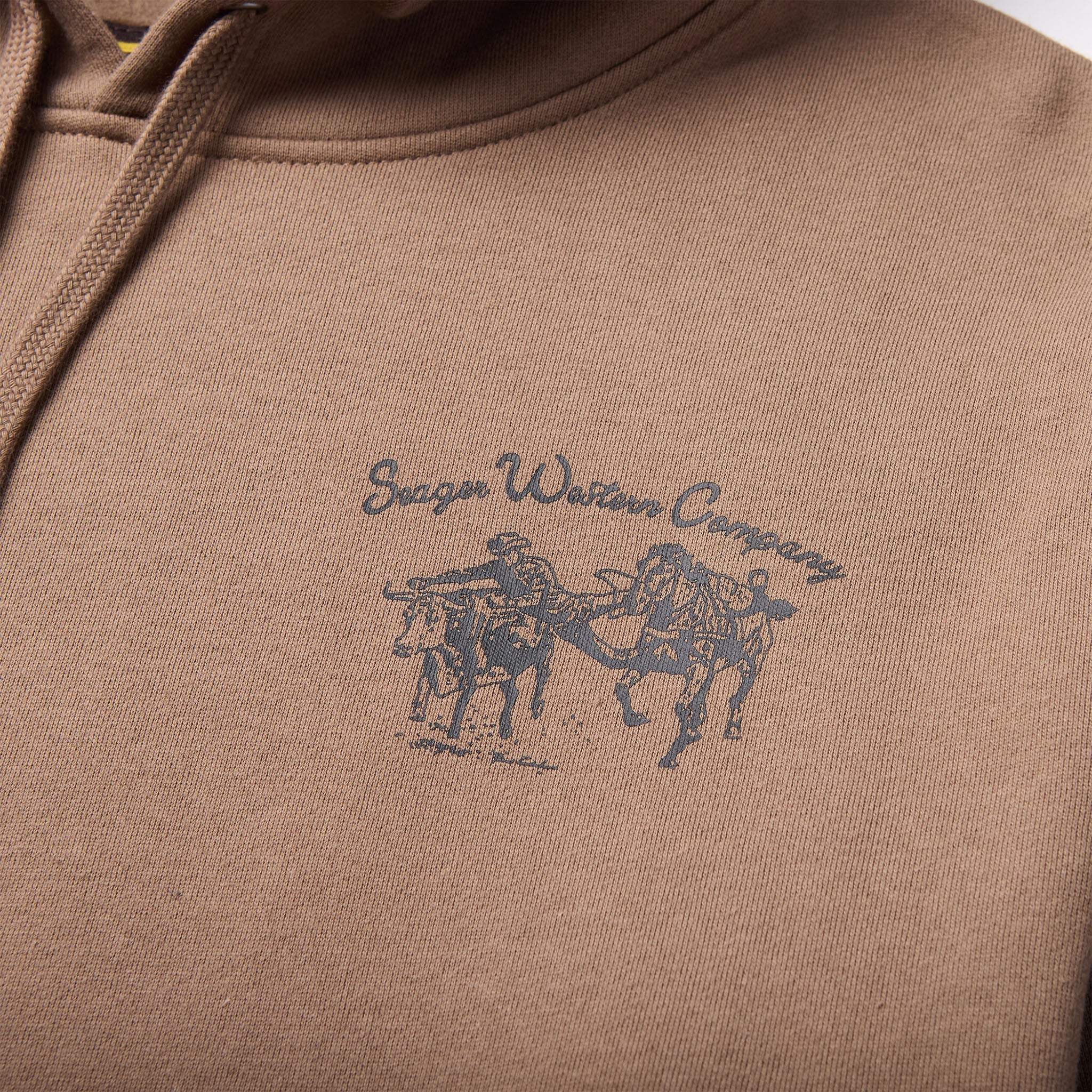 Close-up of Los Rios Black Hoodie showing Embroidered script text and motorcycle racer graphic in blue on tan fabric -