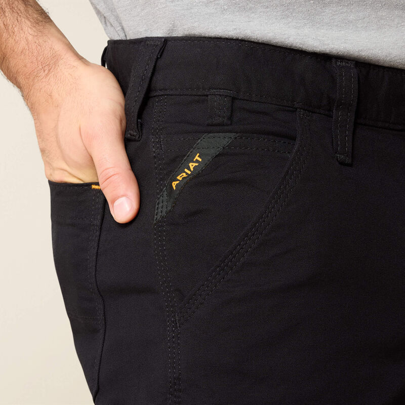 Person wearing M4 Rebar Straight Leg Pants Black Pants, Hand in pocket of black work pants against neutral studio background