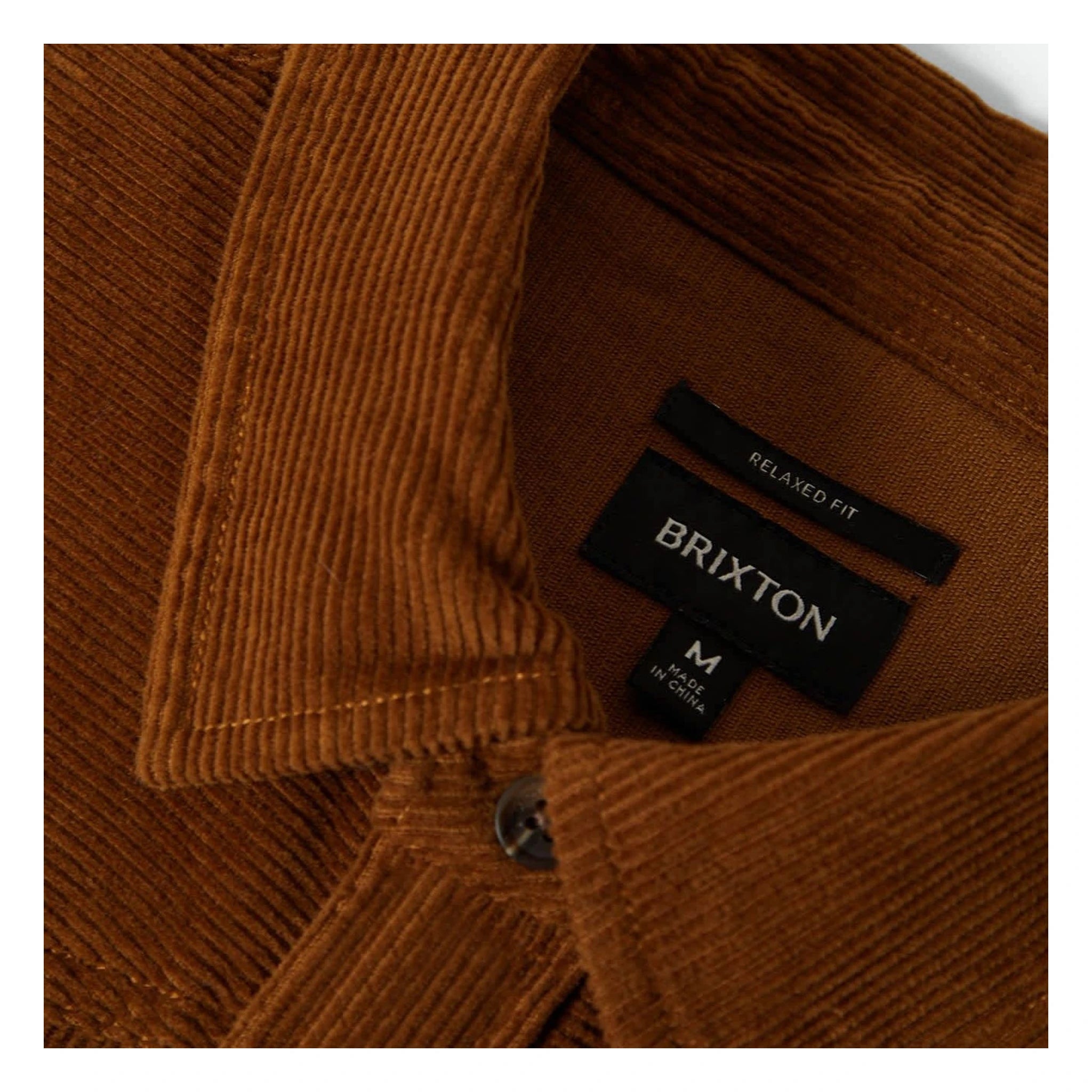 Care label on New West Relaxed Overshirt Washed Copper Cord Jacket showing Black woven label with "RELAXED FIT" above