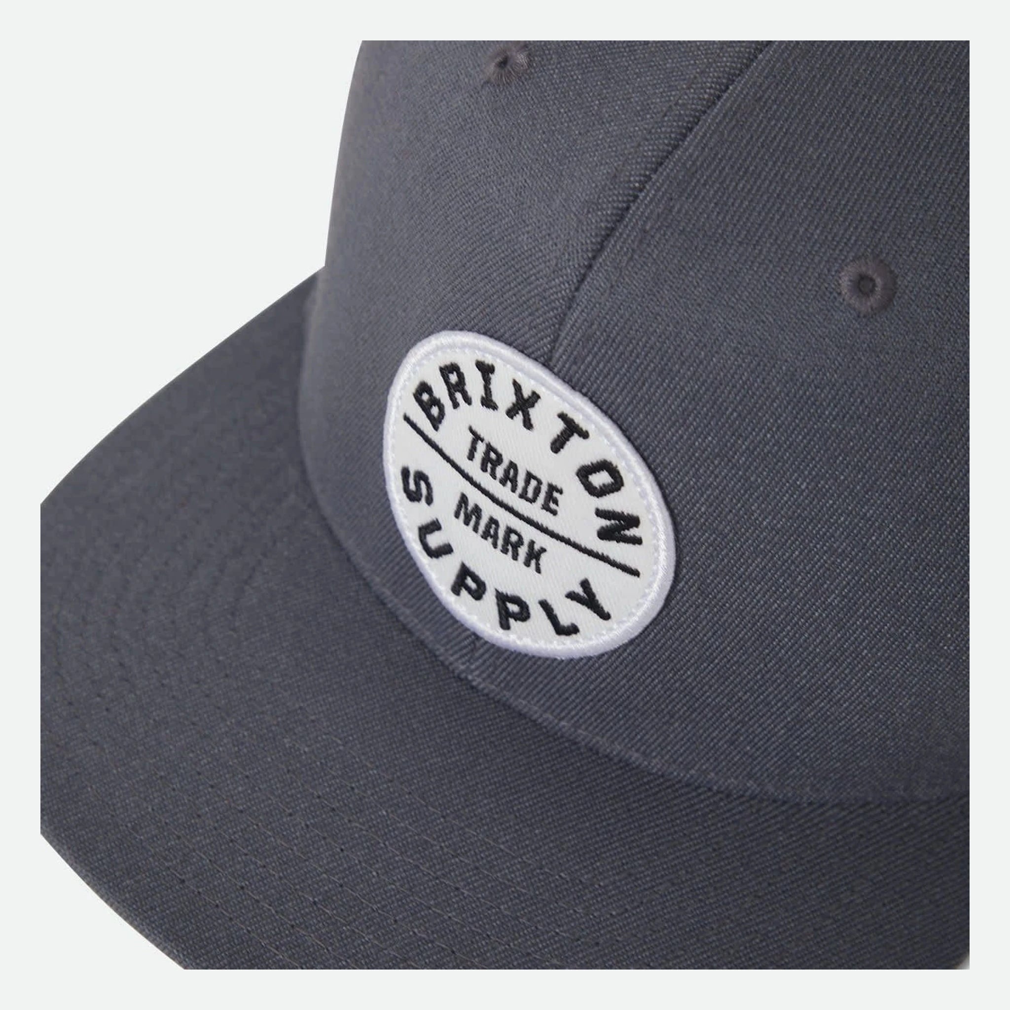 Close-up of Oath III Snapback Khaki/primal Green Hat showing White oval embroidered patch with black text reading "Brixton
