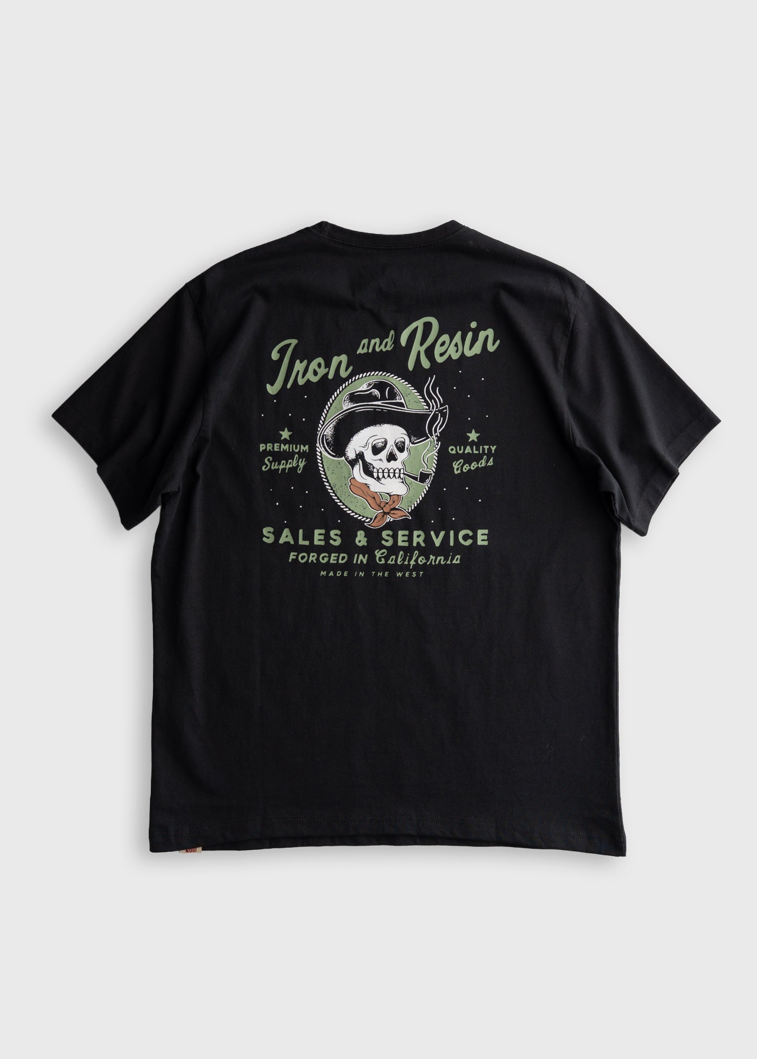 Old Cowboy Pocket front view, Black with sage and cream skull graphic, "Iron and Resin" script, "Sales & Service" text, and