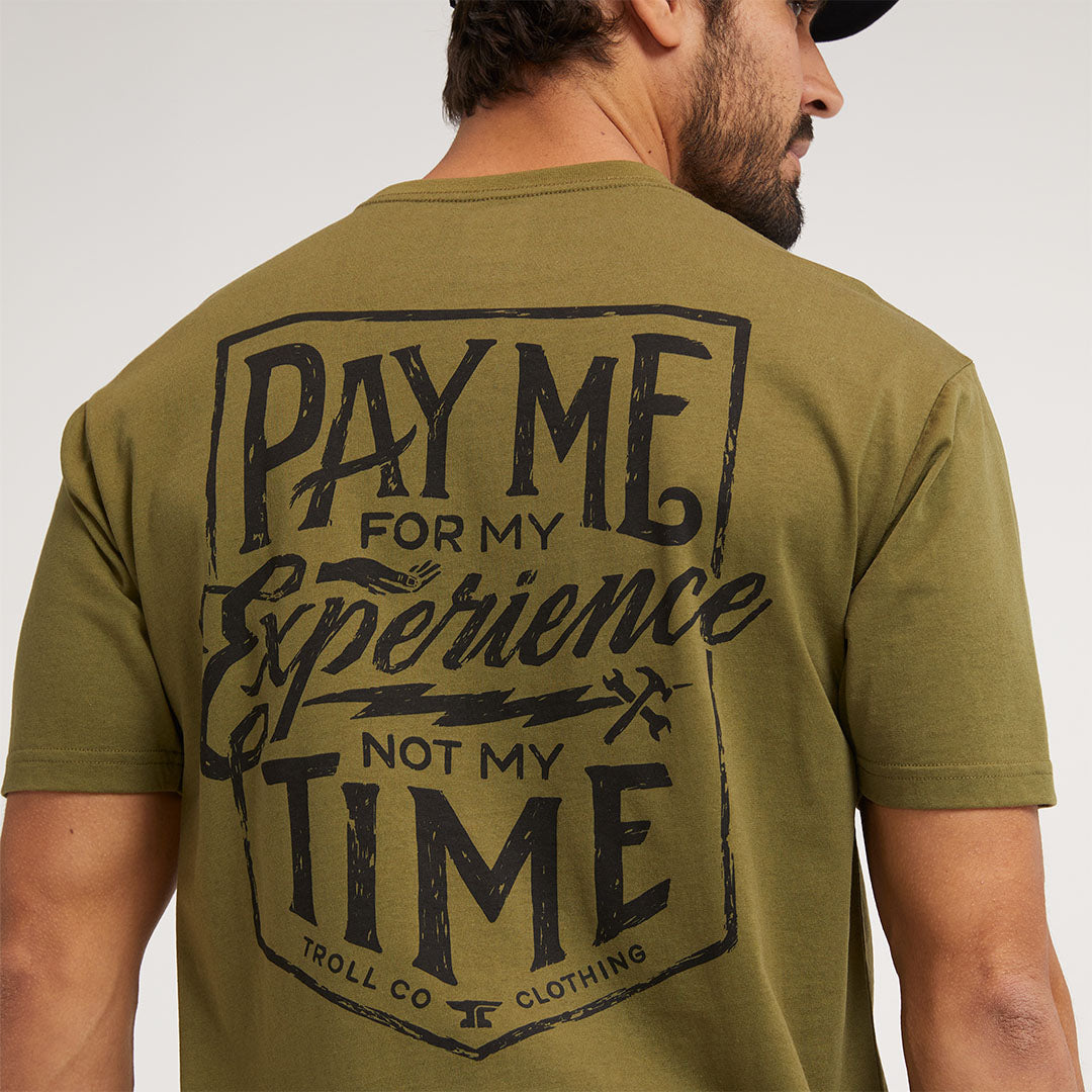 Person wearing Pay Me Military Tee, Man wearing military green tee against neutral studio backdrop - Slowride Supply