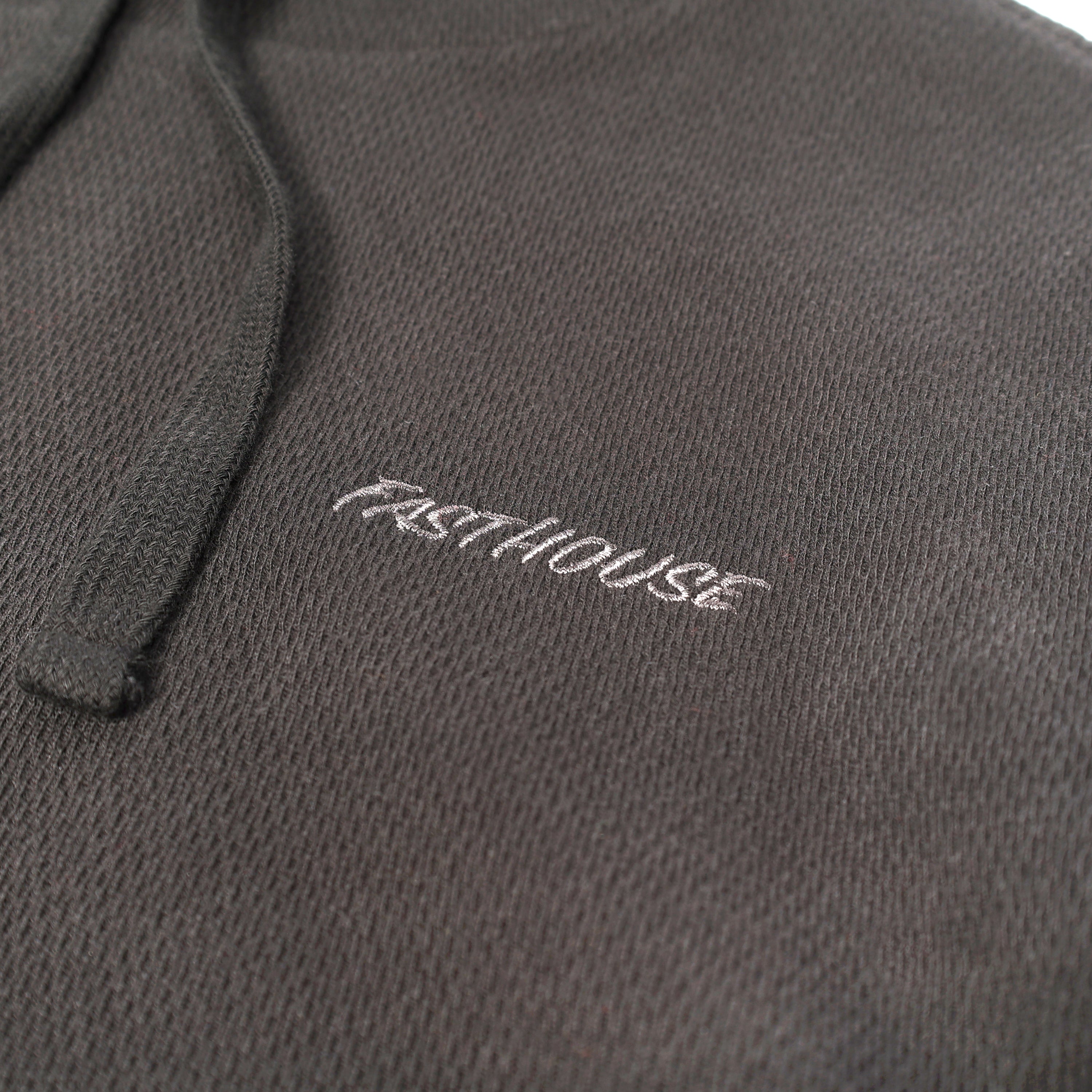 Close-up of Robin Hooded Thermal Apparel Black Apparel showing White embroidered script text on charcoal ribbed knit fabric