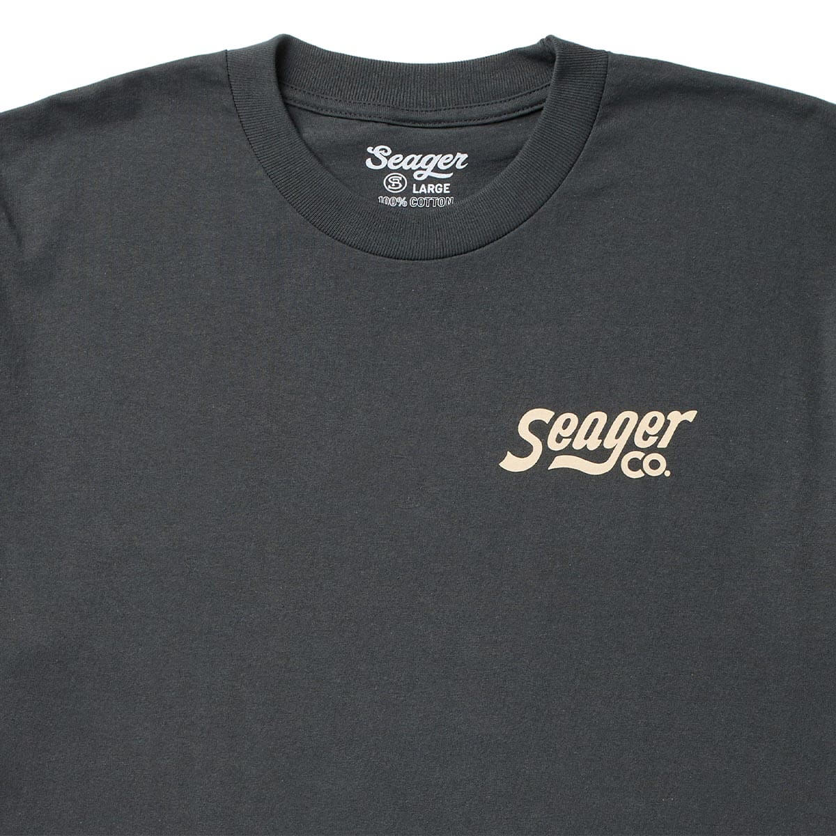 Close-up of Romero White Tee showing Charcoal tee with cream script logo across chest, ribbed crewneck collar, 100% cotton
