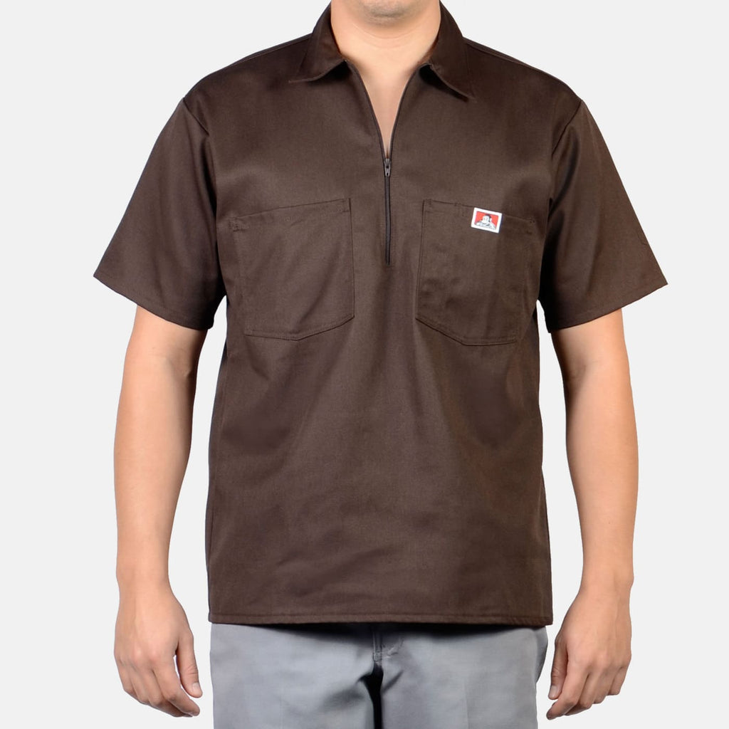Person wearing Short Sleeve Solid Half Zip S/S Woven Black S/S Woven, Neutral studio background with plain gray wall -