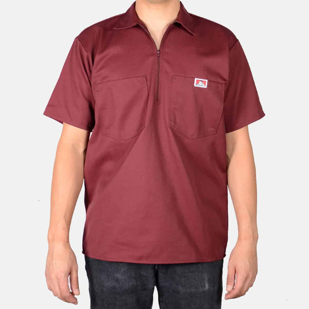 Person wearing Short Sleeve Solid Half Zip S/S Woven Black S/S Woven, Burgundy work shirt displayed against neutral studio