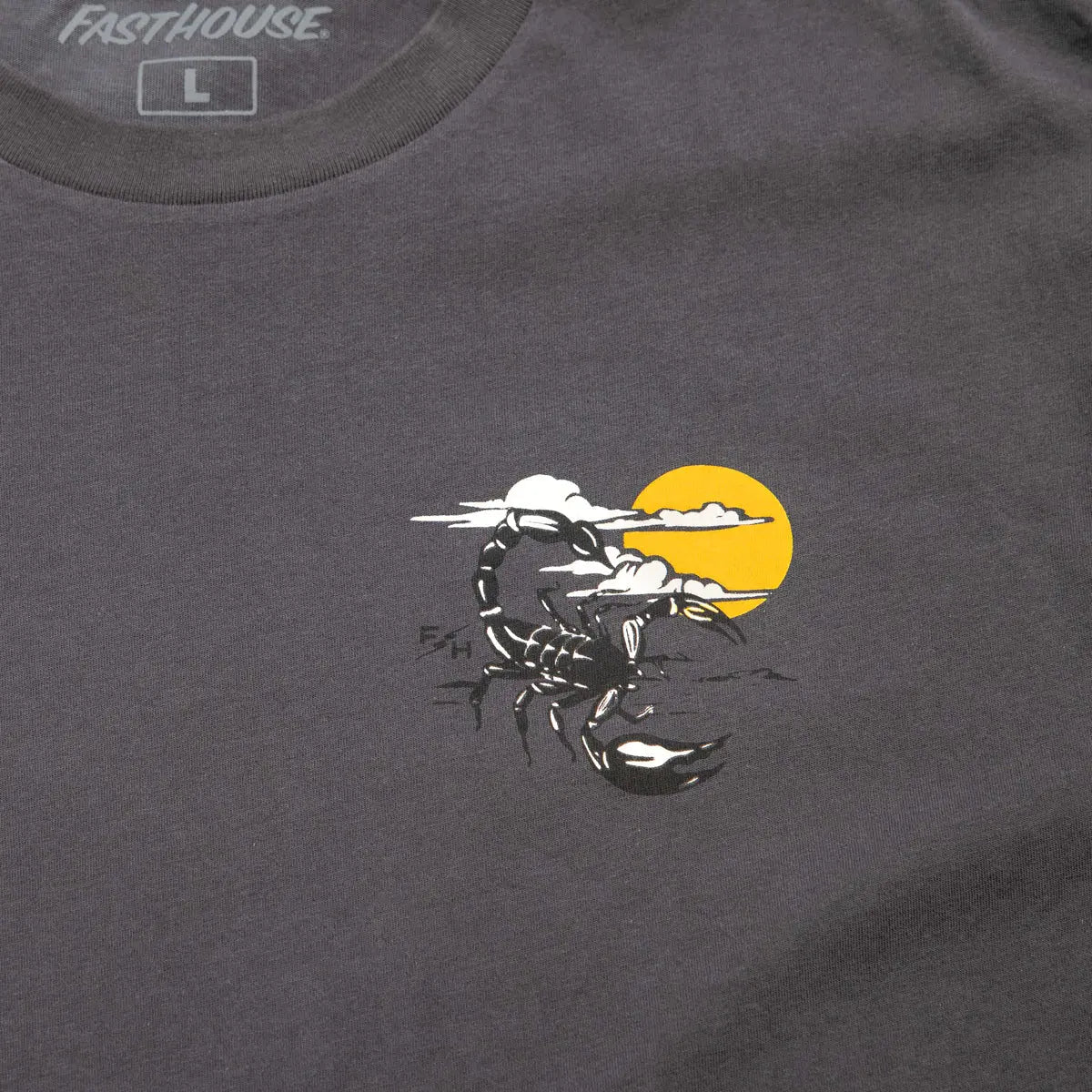 Close-up of Stinger Graphite Black Tee showing Embroidered scorpion silhouette with yellow sun and white cloud details -