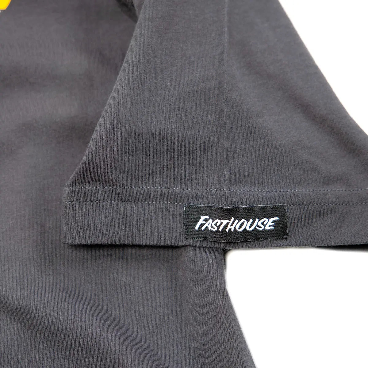 Close-up of Stinger Graphite Black Tee showing Black woven label with white text sewn into gray ribbed fabric seam -