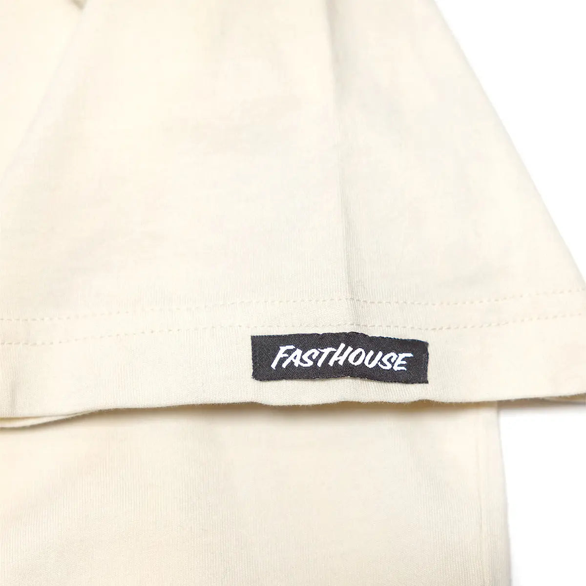 Care label on Tomahawk Natural Tee showing Black woven label with white italic text on cream fabric - Slowride Supply