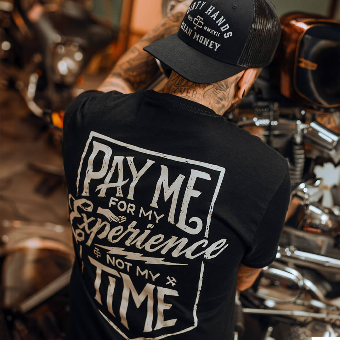 Person wearing DHCM Classic Trucker White/coyote Brown Hat, Garage workshop with motorcycle engine and chrome parts visible