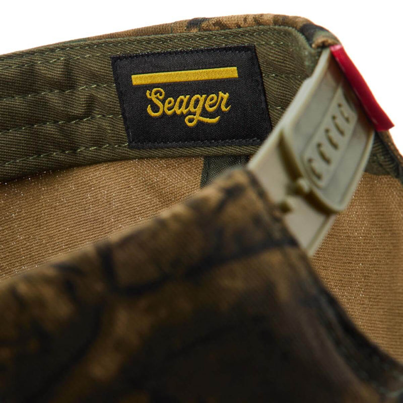 Care label on USA Snapback Camo Hat showing Black woven label with gold script text and yellow stripe detail - Slowride