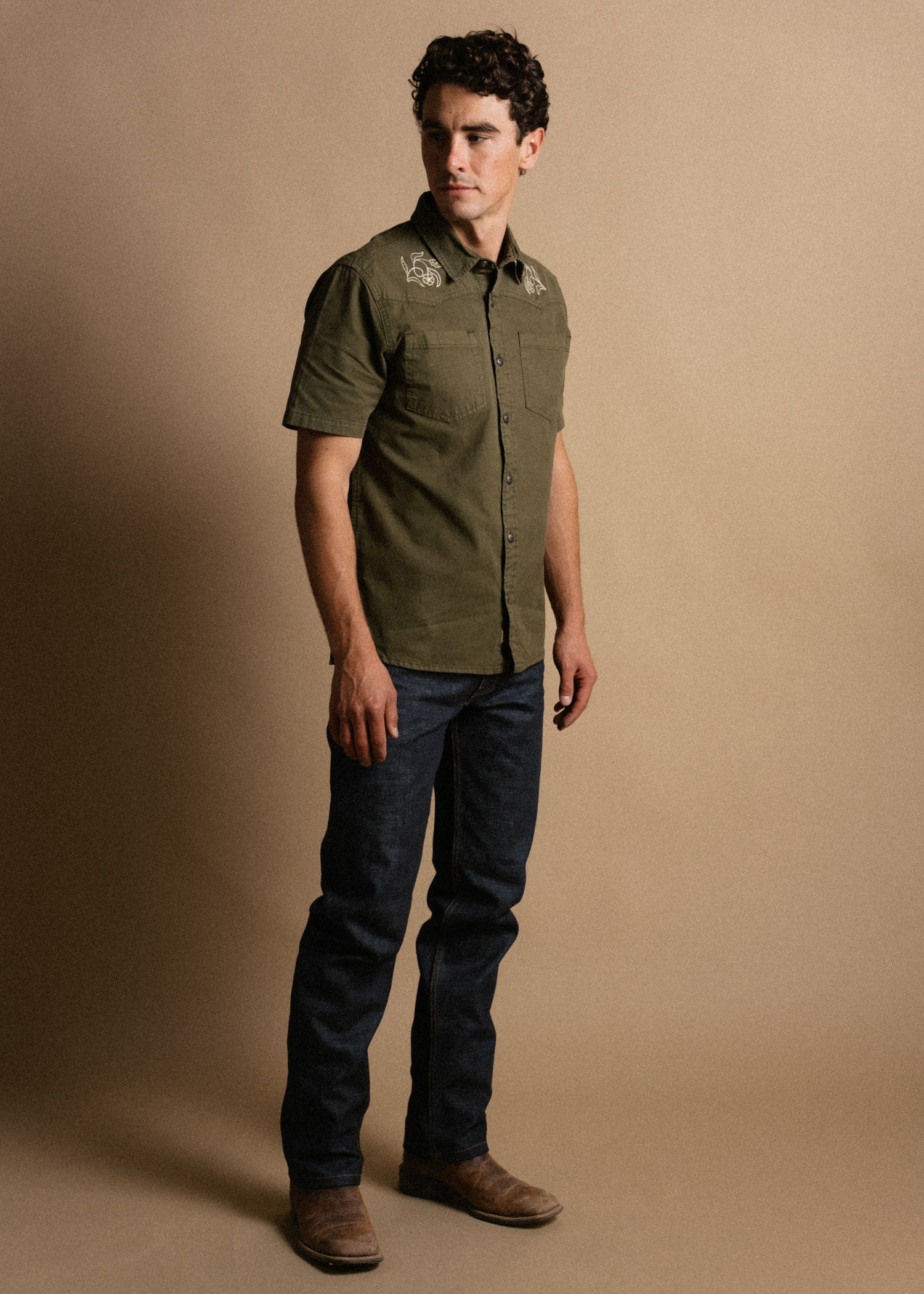 Person wearing Westy Shirt S/S Woven Light Khaki S/S Woven, Neutral studio setting with soft beige backdrop, model standing