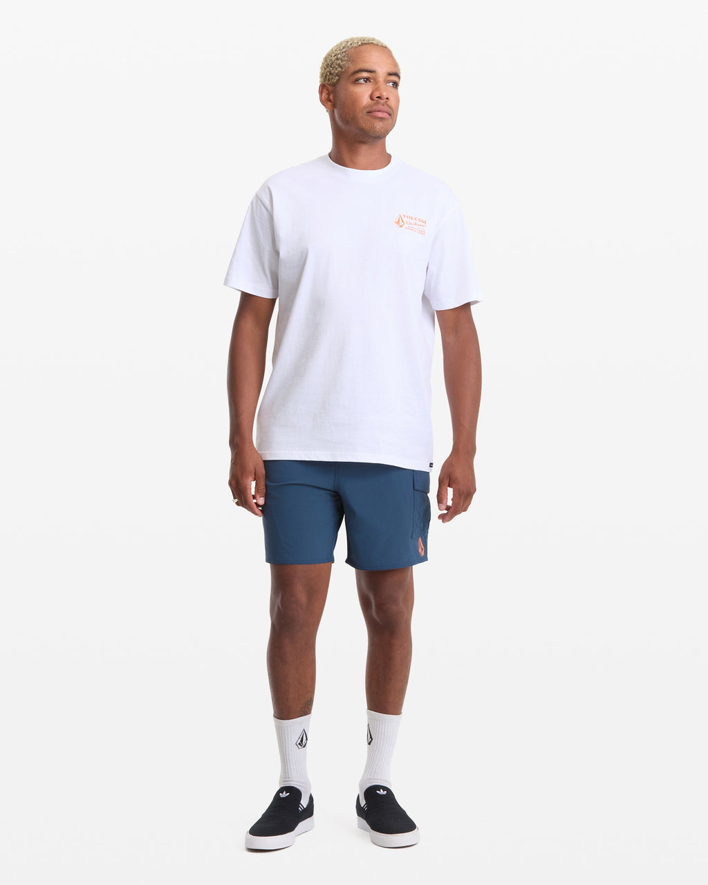 Person wearing Workwear White Tee, Man wearing white tee with small orange chest graphic, styled against plain white studio