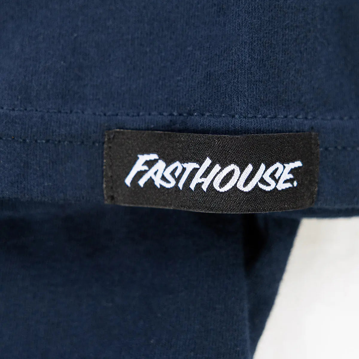 Care label on Youth Team Tee Navy Kids Navy Kids Tee showing Black woven label with white script text reading "Fasthouse -