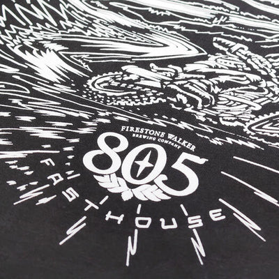 Close-up of 805 Desert Run Black Tee showing White woodcut-style graphic with radiating speed lines and winged emblem motif