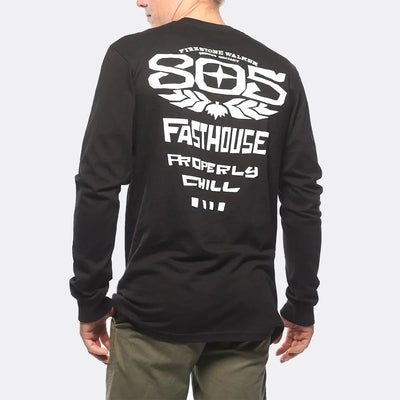 Person wearing 805 Gravel Black L/S Tee, Wearer standing outdoors against neutral light background, showing back graphic