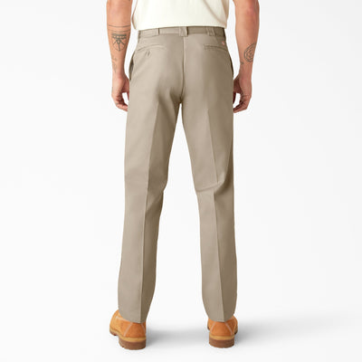 Person wearing 874f - Flex Work Pant Pants Dark Navy Pants, Man wearing cream tee and tan work pants, standing against white