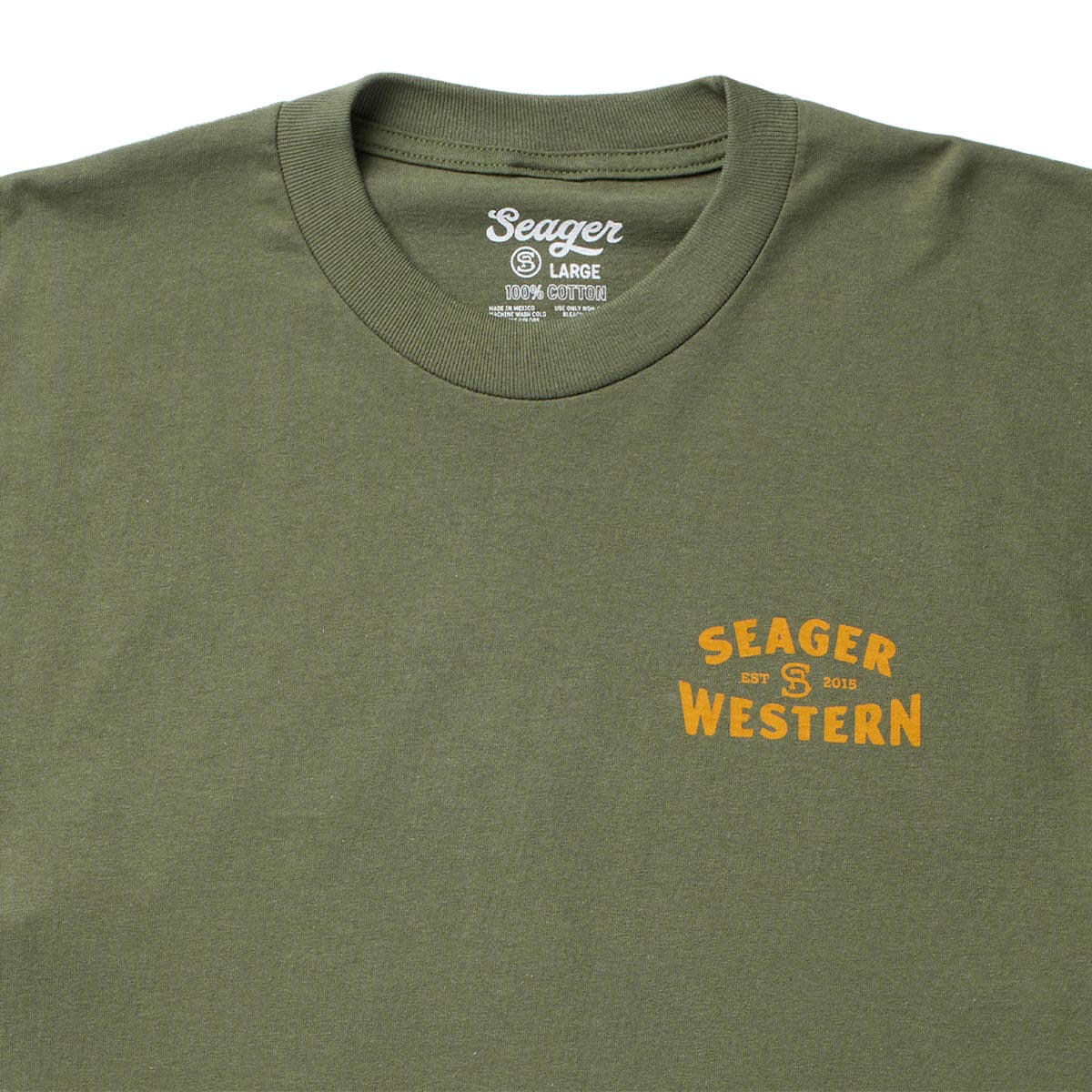 Close-up of Americas Choice Surplus Green Tee showing Surplus green cotton tee with gold chest print reading "Seager