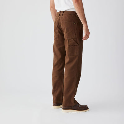 Person wearing Bison Canvas Pants Brown Pants, Plain white studio backdrop with neutral lighting - Slowride Supply