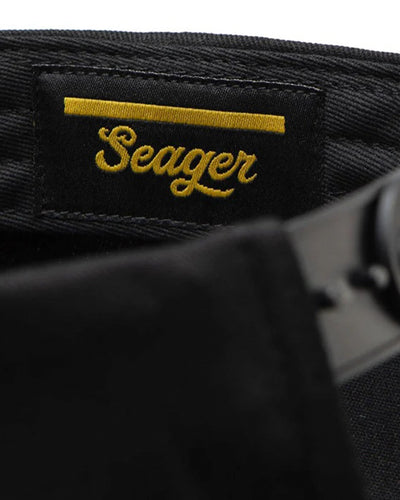 Care label on Bradley Snapback Black Hat showing Black woven label with gold embroidered script text and horizontal stripe