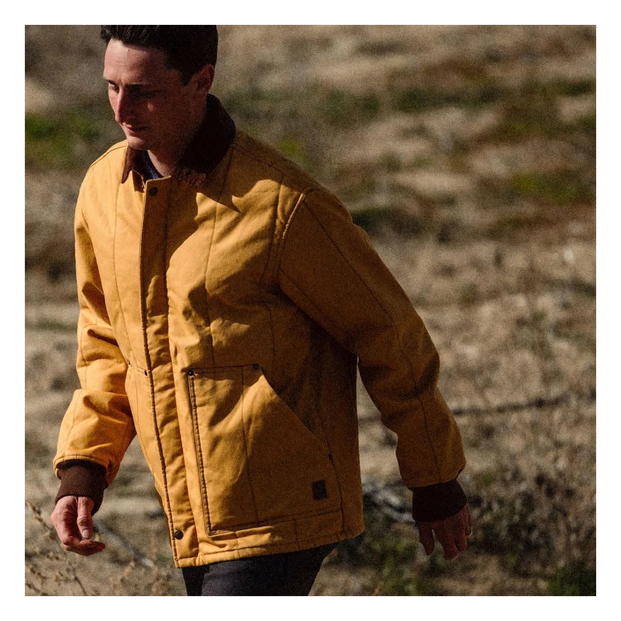 Person wearing Builders Ranch Jacket Spruce Yellow Jacket, Man wearing yellow jacket standing in sparse desert landscape