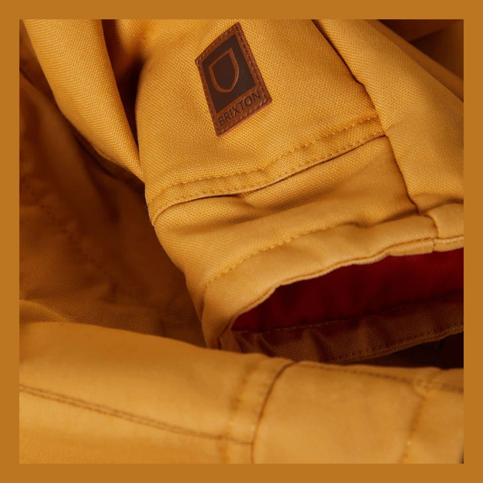 Close-up of Builders Ranch Jacket Spruce Yellow Jacket showing Brown leather patch label with teardrop logo and text on