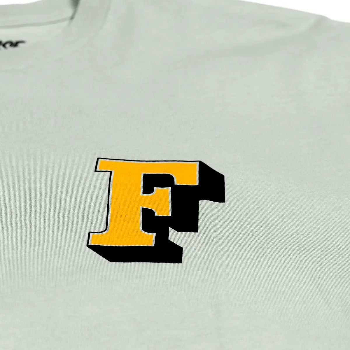 Close-up of Champions Choice Sage Tee showing Embroidered yellow and black letter F with white outline on chest - Slowride