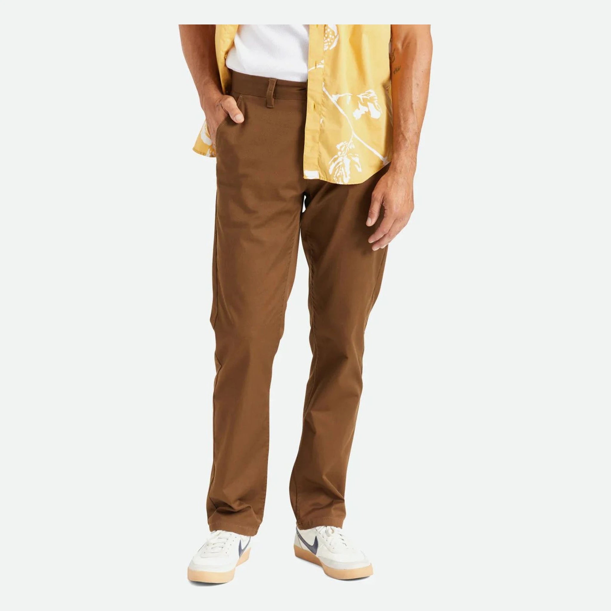 Person wearing Choice Chino Pant Pants Black Pants, Man wearing brown chinos and white sneakers against neutral background -