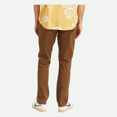 Person wearing Choice Chino Pant Pants Black Pants, Man standing against plain white backdrop wearing brown chinos and