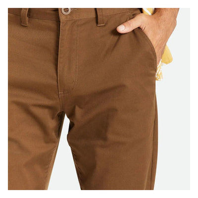 Person wearing Choice Chino Pant Pants Black Pants, Man's hand in pocket of tan chino trousers against neutral background -