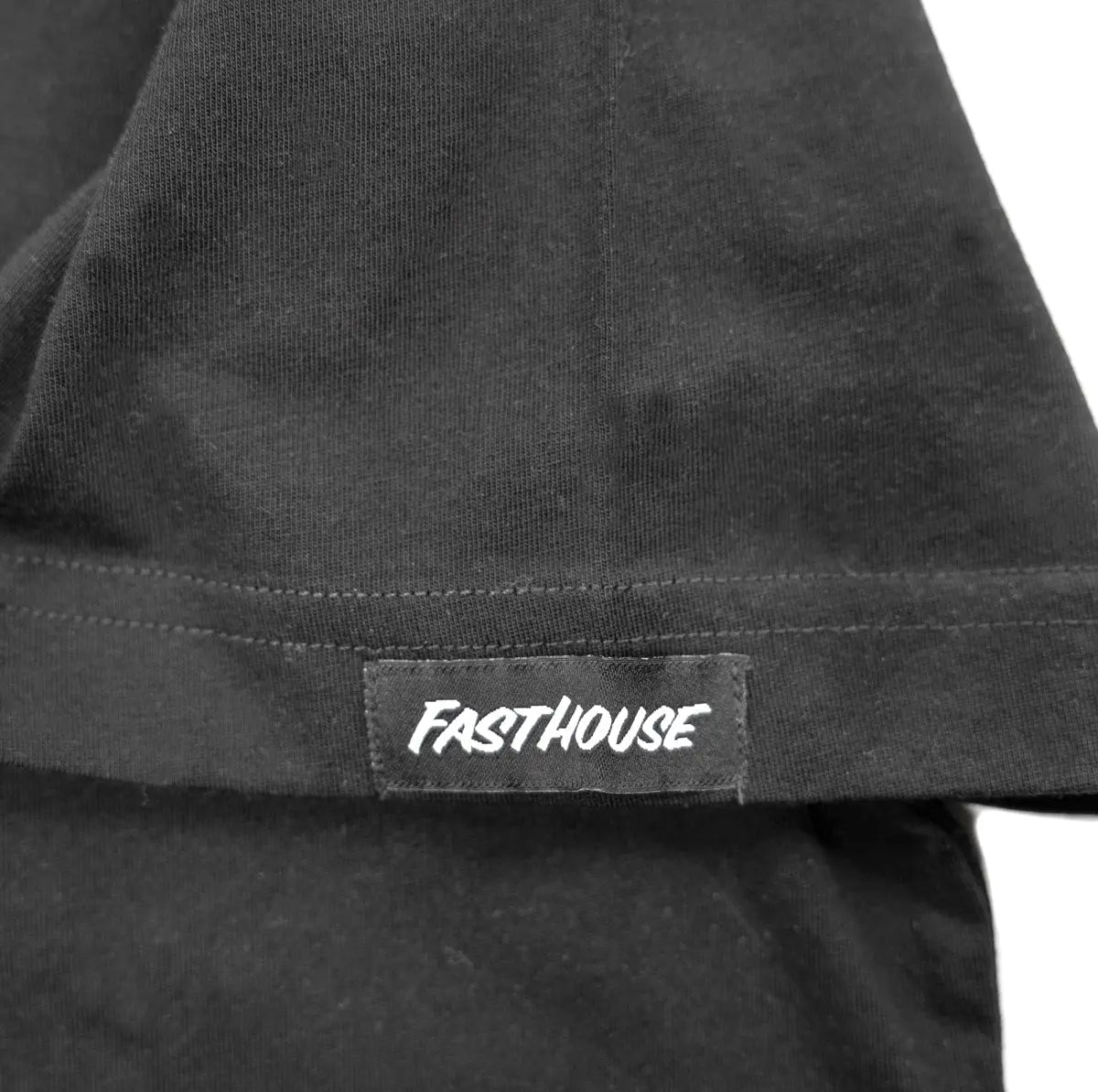 Close-up of Crown White Tee showing White woven label with italic text on charcoal ribbed hem band - Slowride Supply