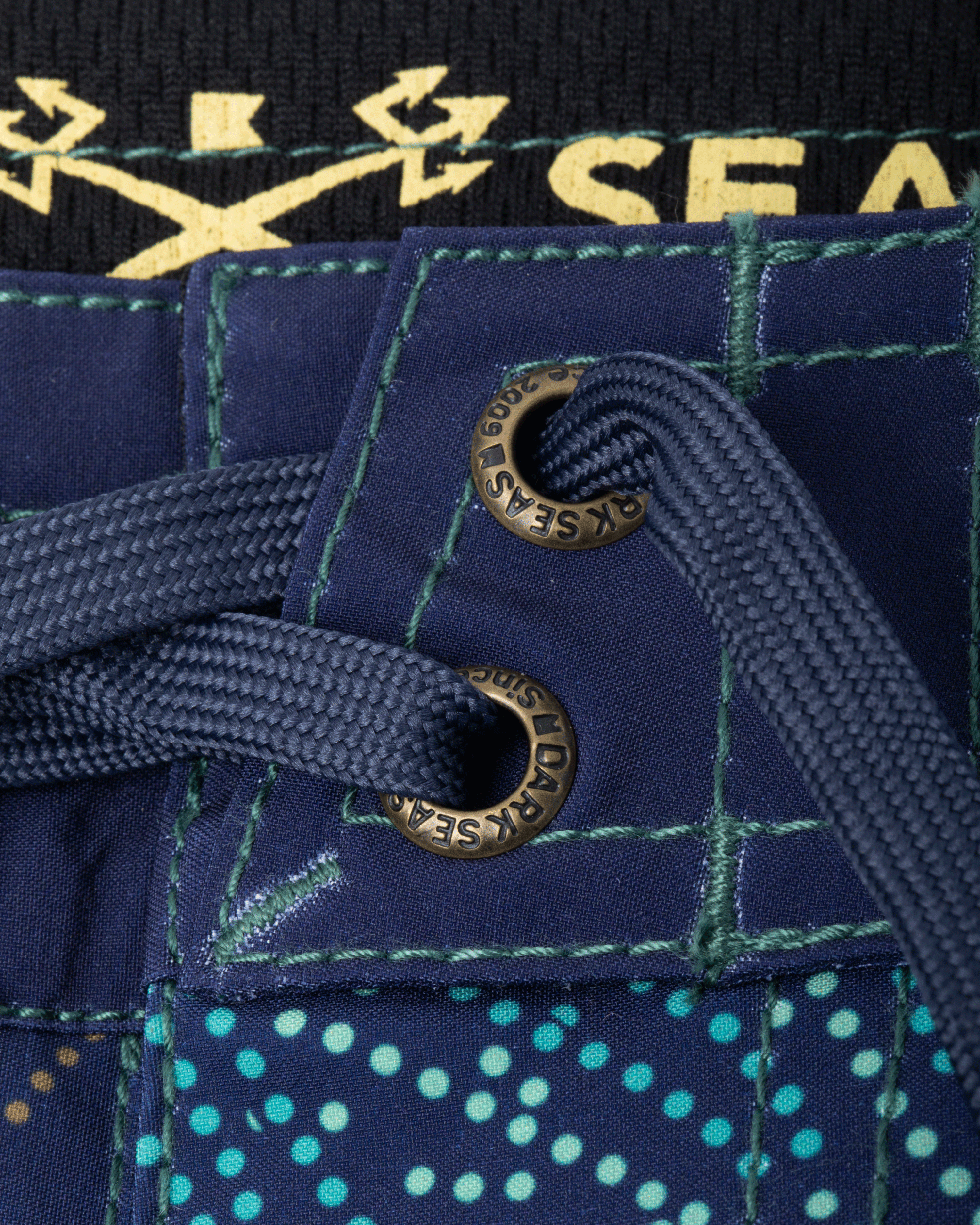 Close-up of Deepwater Boardshort Boardshorts Navy Boardshorts showing Brass grommet with green cord drawstring on navy