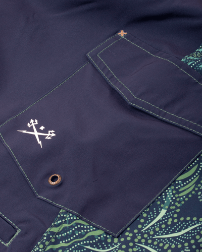 Close-up of Deepwater Boardshort Boardshorts Navy Boardshorts showing Embroidered cross logo on front pocket with brass