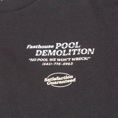 Close-up of Demolition Black Tee showing White screen-printed text and badge on charcoal ribbed cotton fabric, phone number