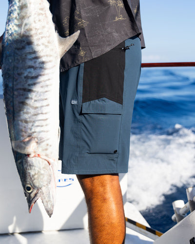 Person wearing Flagship Boatshort 19" Boardshorts Navy Boardshorts, Person on fishing boat holding large caught fish, ocean