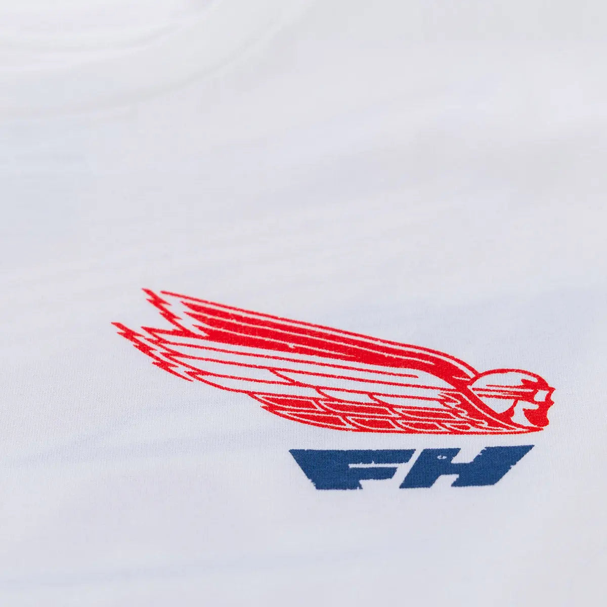 Close-up of Flyer White Tee showing Red winged emblem with blue text underneath, embroidered on white fabric - Slowride