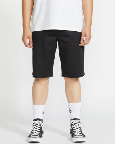 Person wearing Frickin Modern Short Shorts Black Shorts, Man standing against neutral backdrop wearing black shorts with