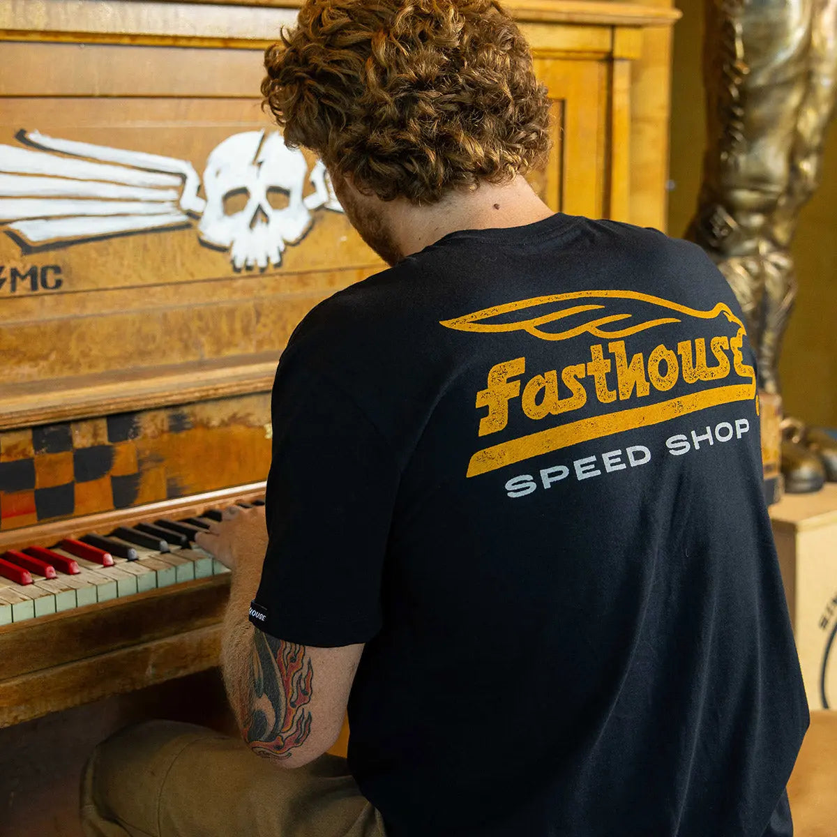Back of Gilmore Black Tee, Black with gold streaked "Fastthouse" text and gold speed line graphic, white "Speed Shop"