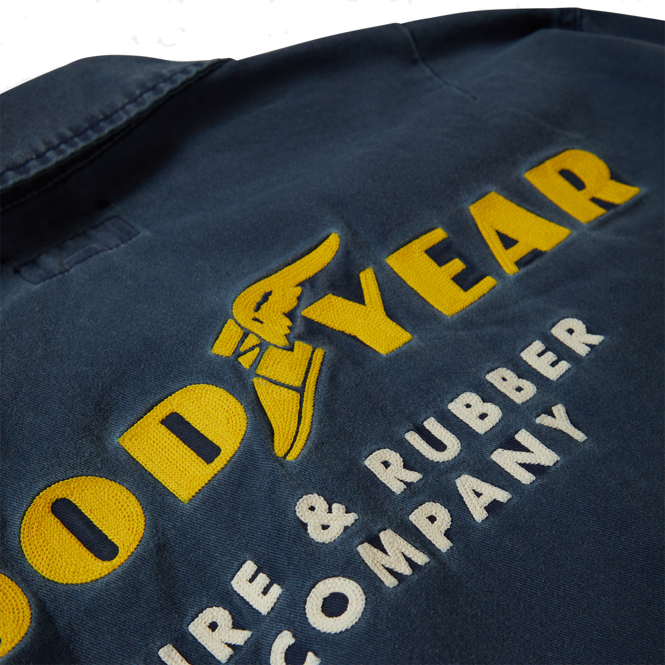 Close-up of Goodyear Trademark LW Washed Navy Jacket showing Embroidered yellow and cream text with winged tire graphic on