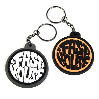 Grime Keychain Accessory front view, Two rubber keychains with cracked text design, one white on black, one gold on black,